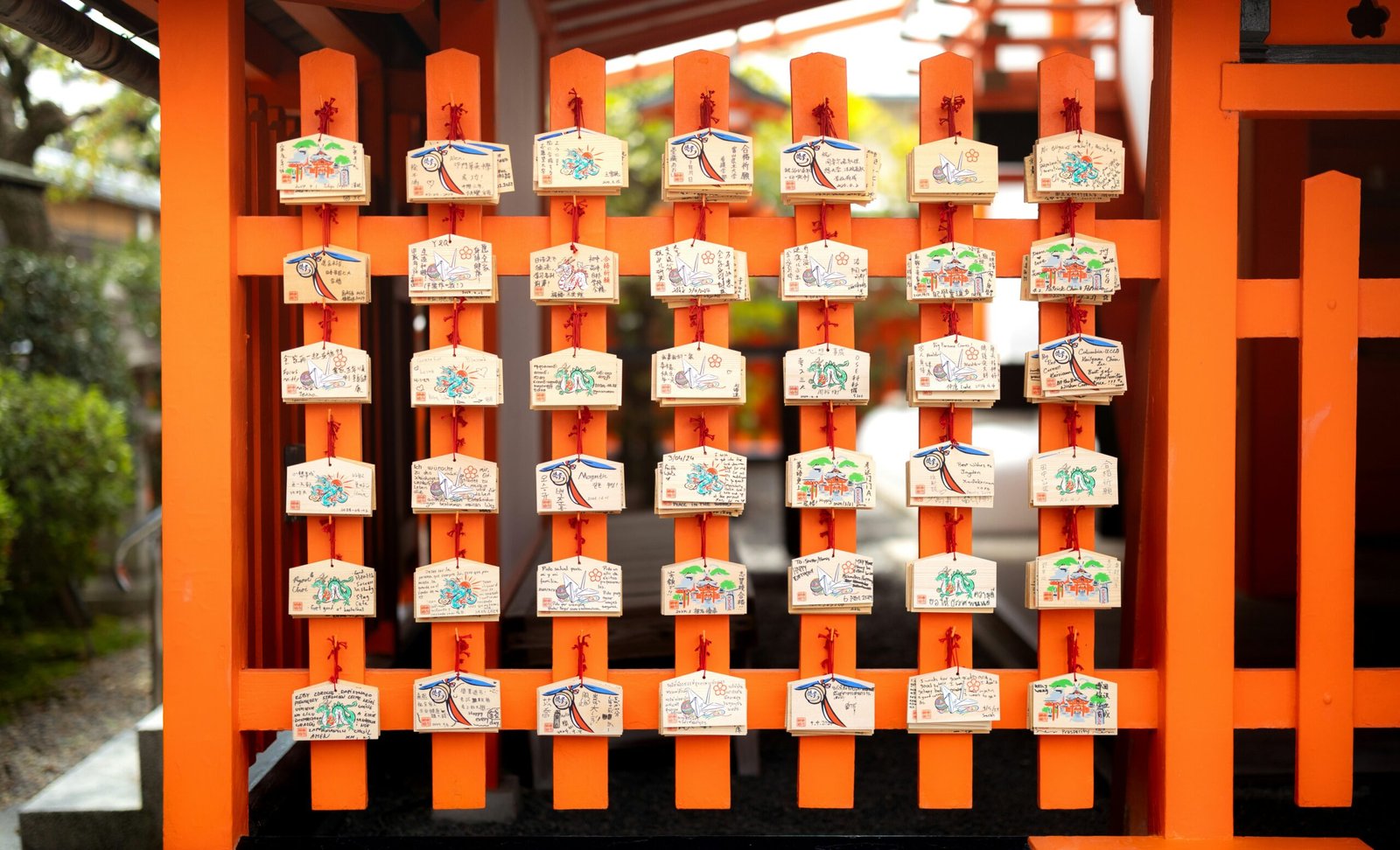 Japanese wooden prayer plaques hang on an orange frame.
